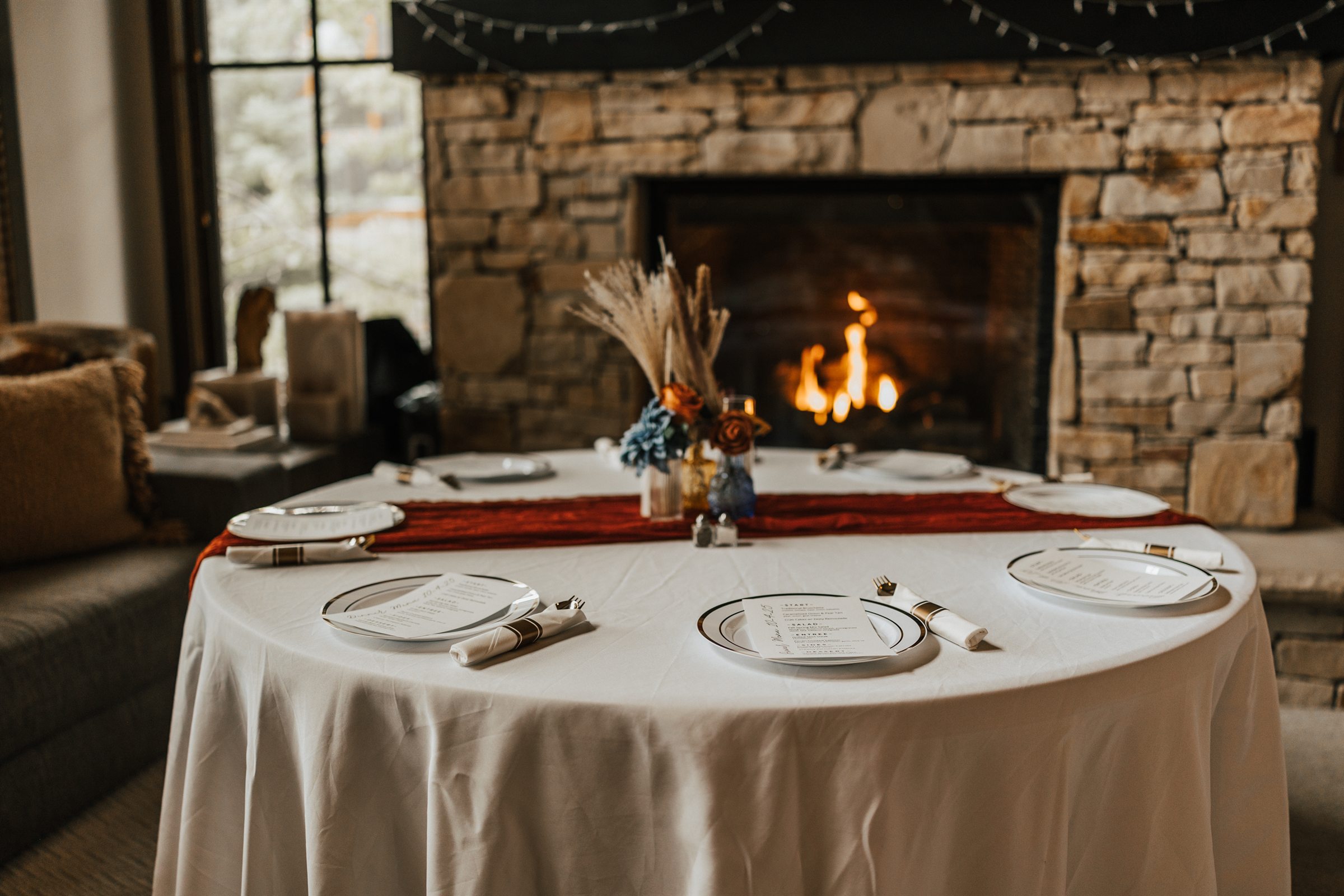 An intimate dining table set beside a stone fireplace
